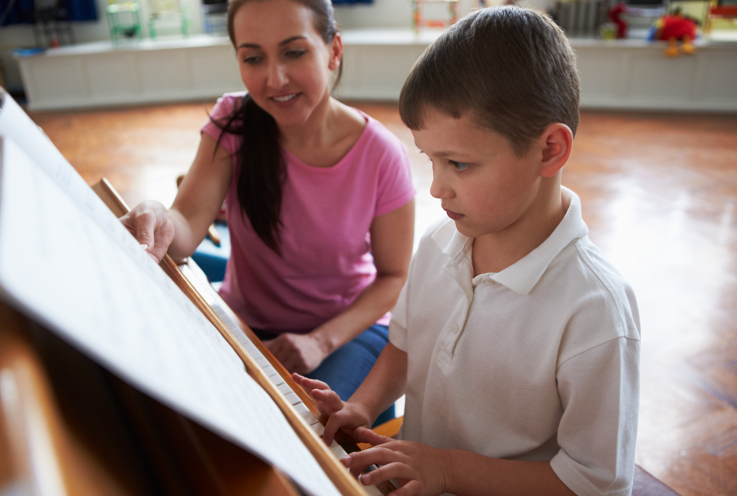 Piano Teacher Pointing Out Music Bars To Boy On The Piano, Families Make Many Mistakes When Paying For Private Piano Lessons