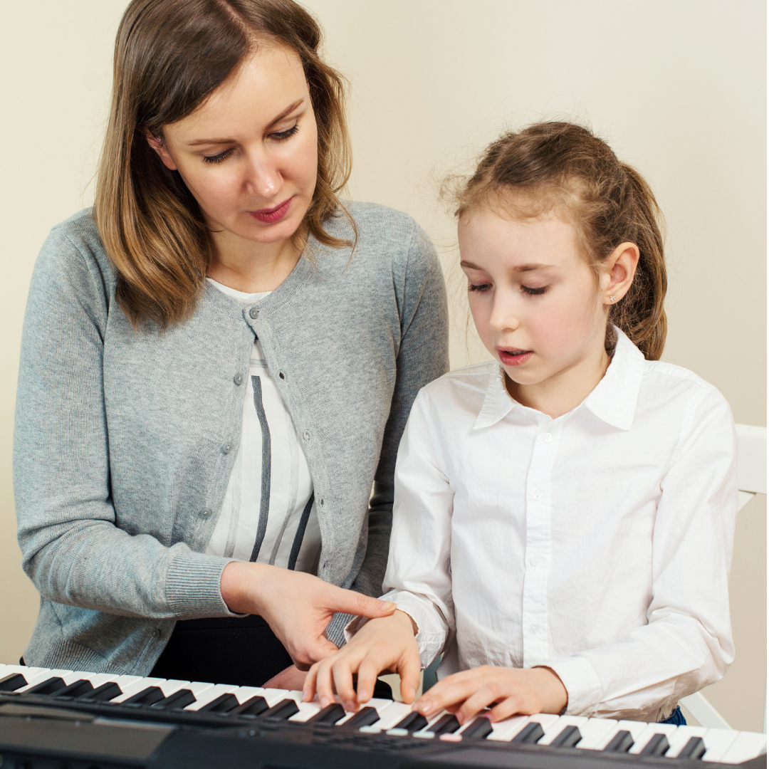 Girl being guided by music teacher on an electric keyboard, why your child needs to create her own music