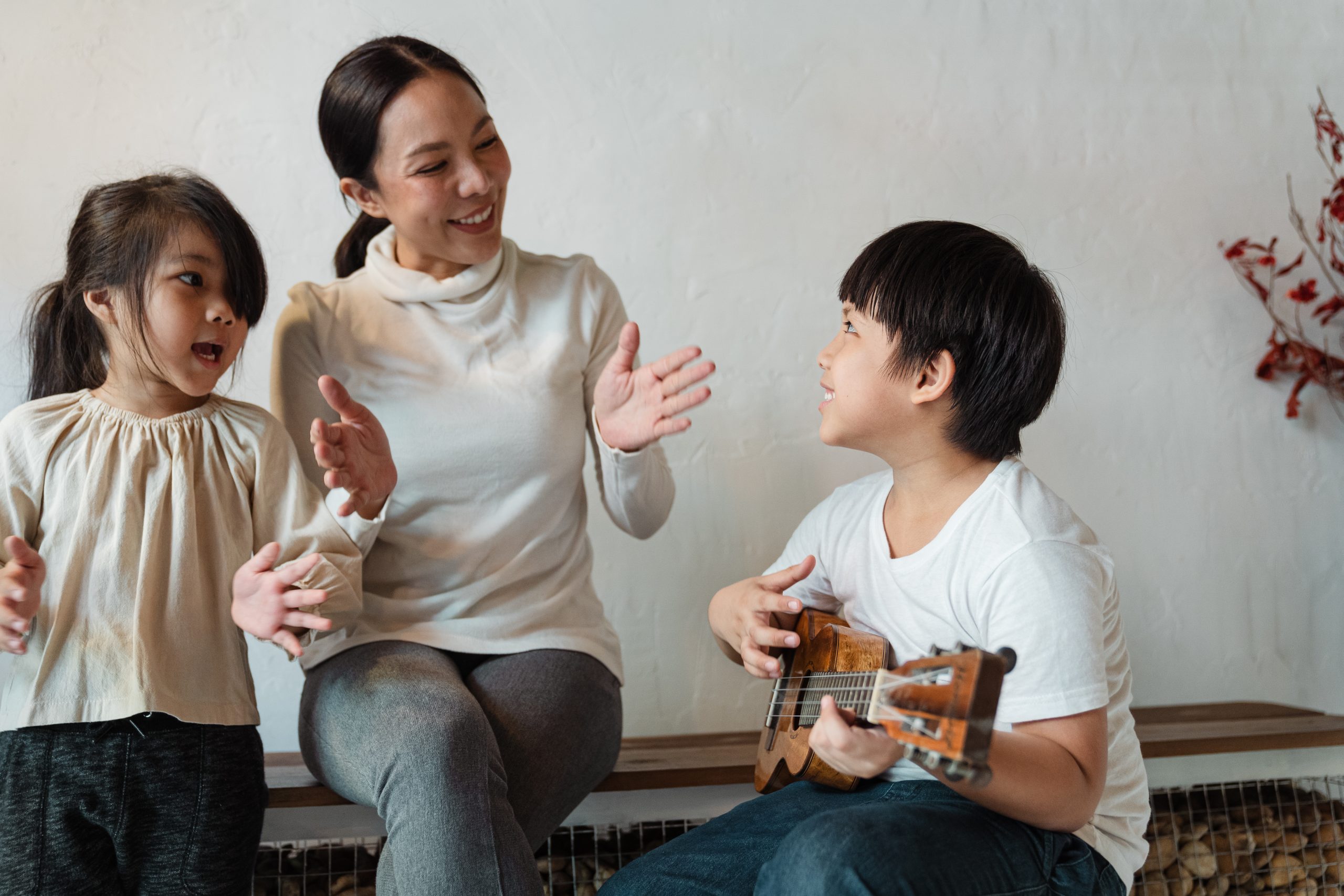Mother And Little Girl Clapping And Singing While Boy Plays Ukulele - Teach Rhythm And Beat In The Homeschool