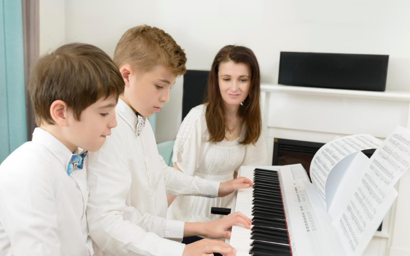 Two Boys Dressed In White With Their Mom, Learning To Play The Piano In The Homeschool